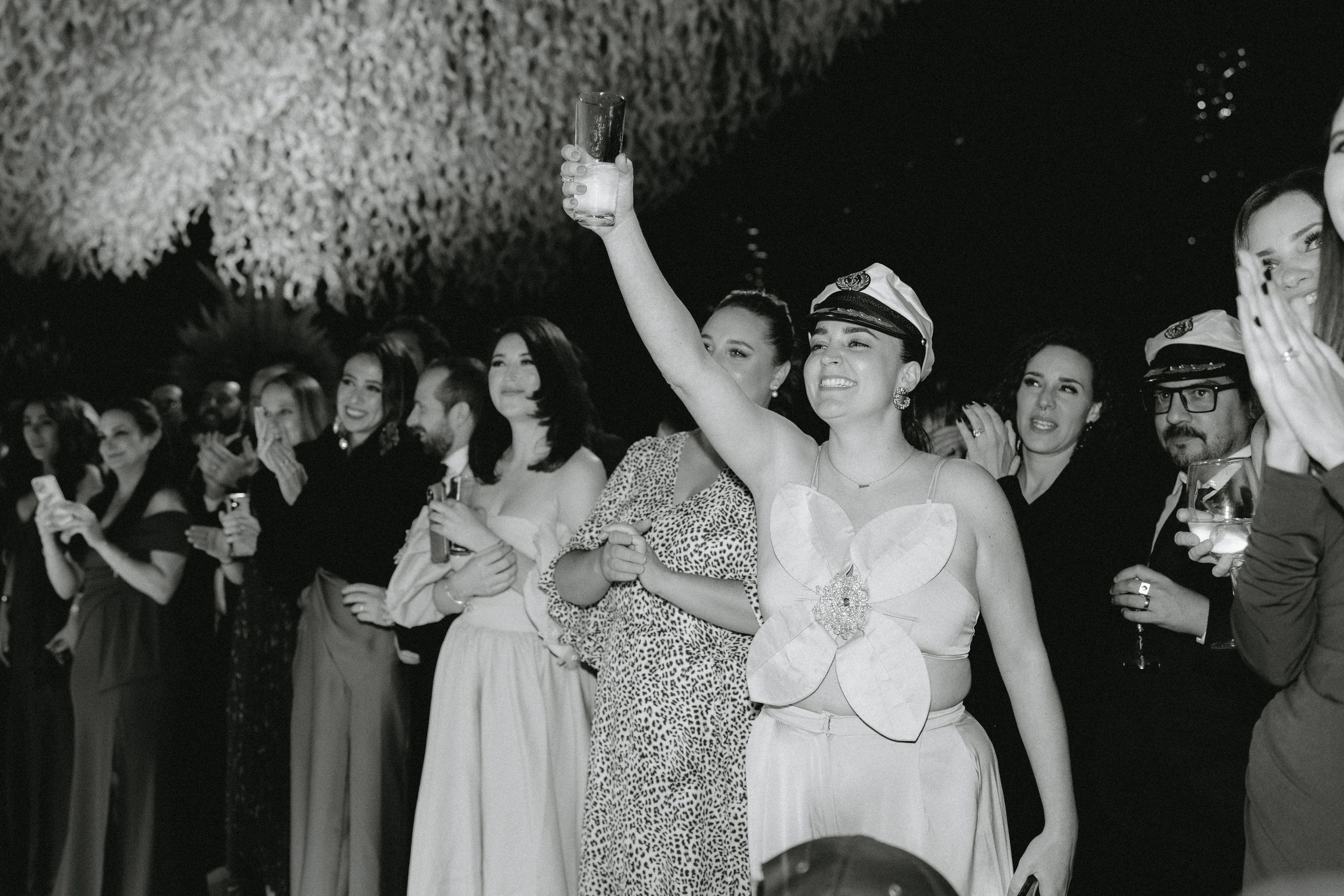 A black and white photograph showing people celebrating at a party with someone raising their hand in the air.