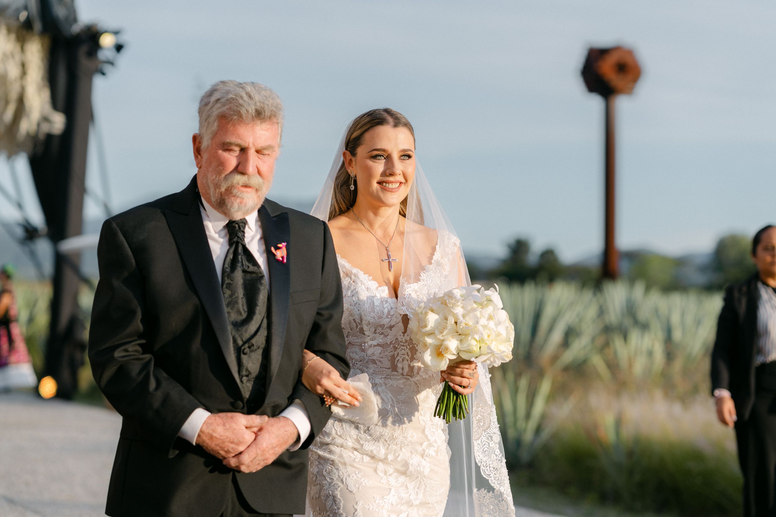 Padre y novia tomada del brazo en una ceremonia de boda al aire libre, un momento hermoso capturado por Alejandro e Ivonne