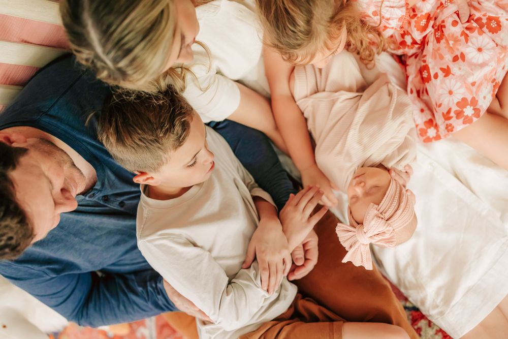 A group lies together comfortably in coordinating outfits of white and navy blue for a relaxed indoor photo session.