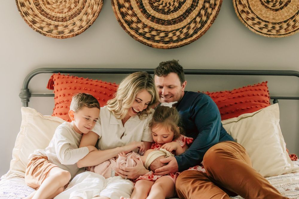 Cozy family moment on bed with decorative woven baskets on wall and coral accent pillows.
