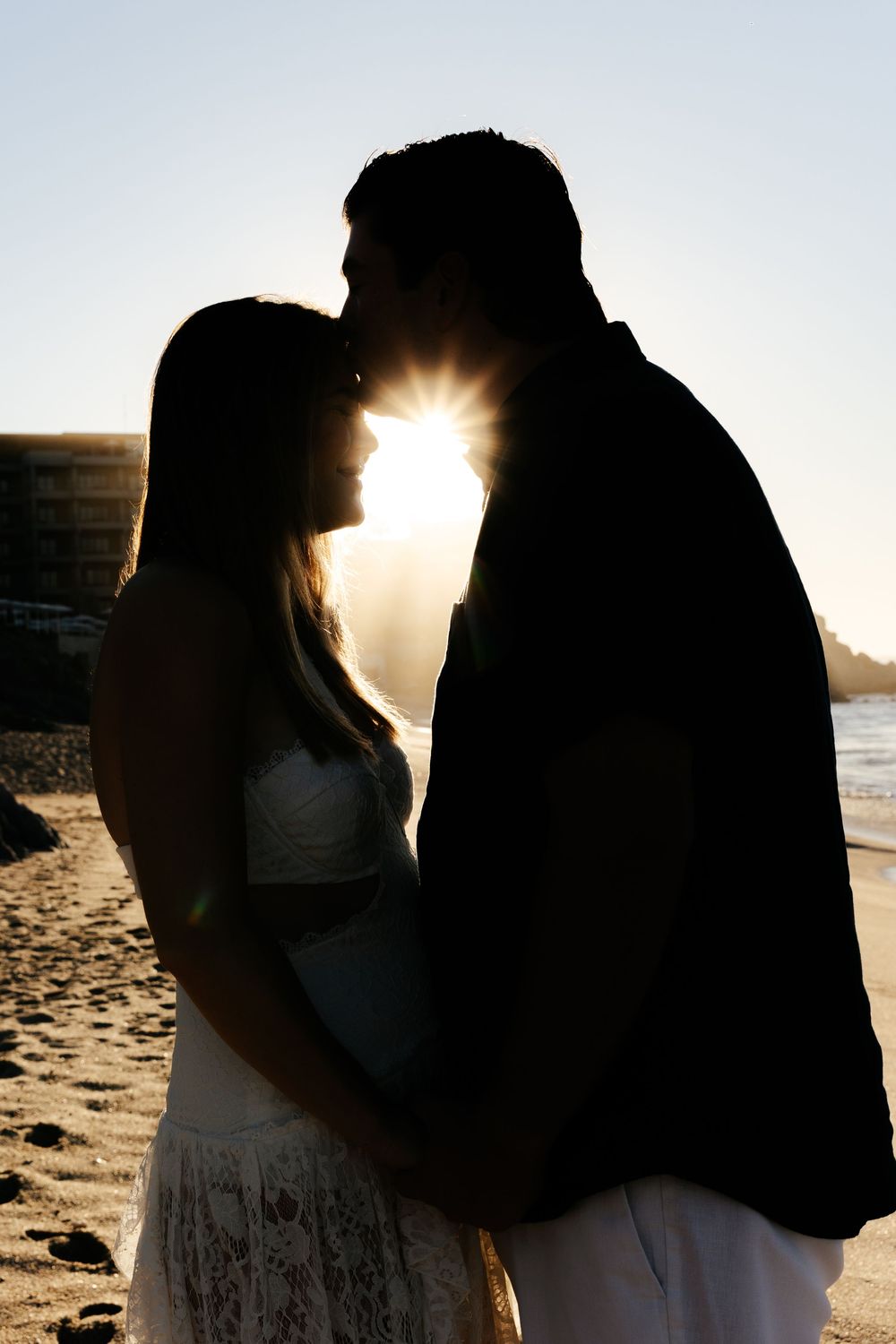 Silhouettes of a couple embracing on a beach at sunset with sun flare creating romantic backlighting in multiple shots.