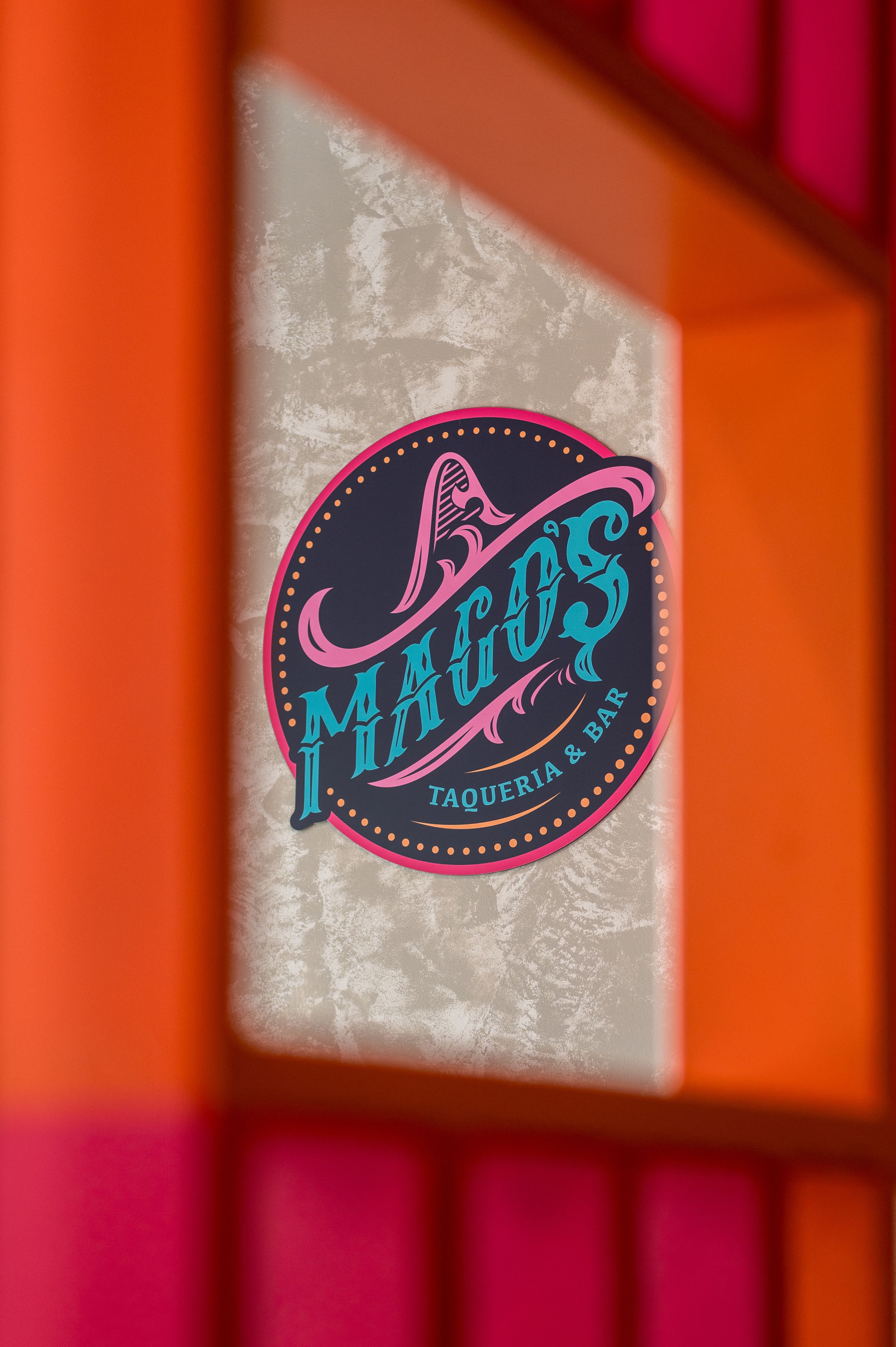 Colorful circular logo sign for 3 Magos Taqueria & Bar with teal and pink lettering on dark background.