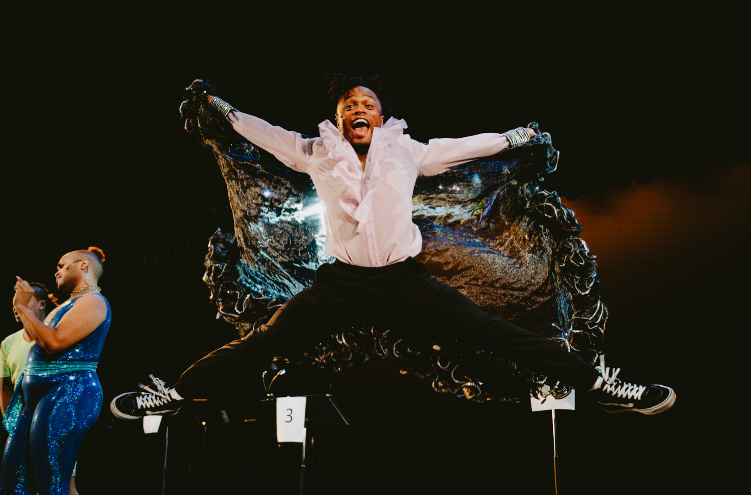 a performer leaping into the air with great excitement during a rehearsal of a play