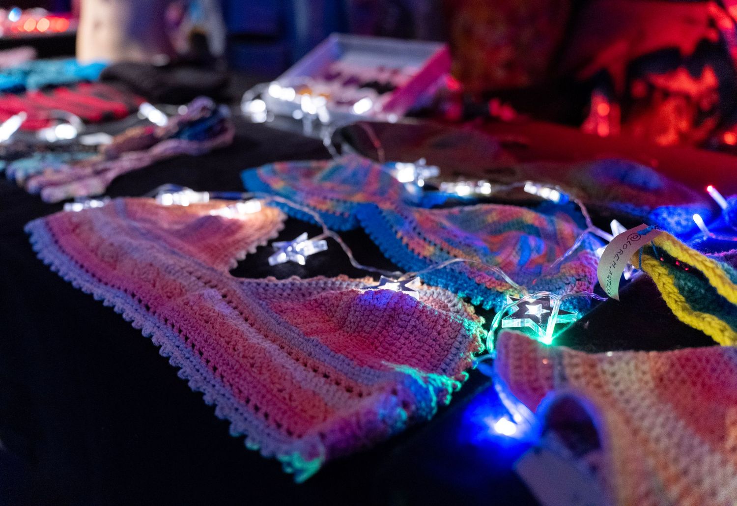 Close-up of flashing LED light-up embroidered tops and hats on a table at a psy handmade party dark event. modem