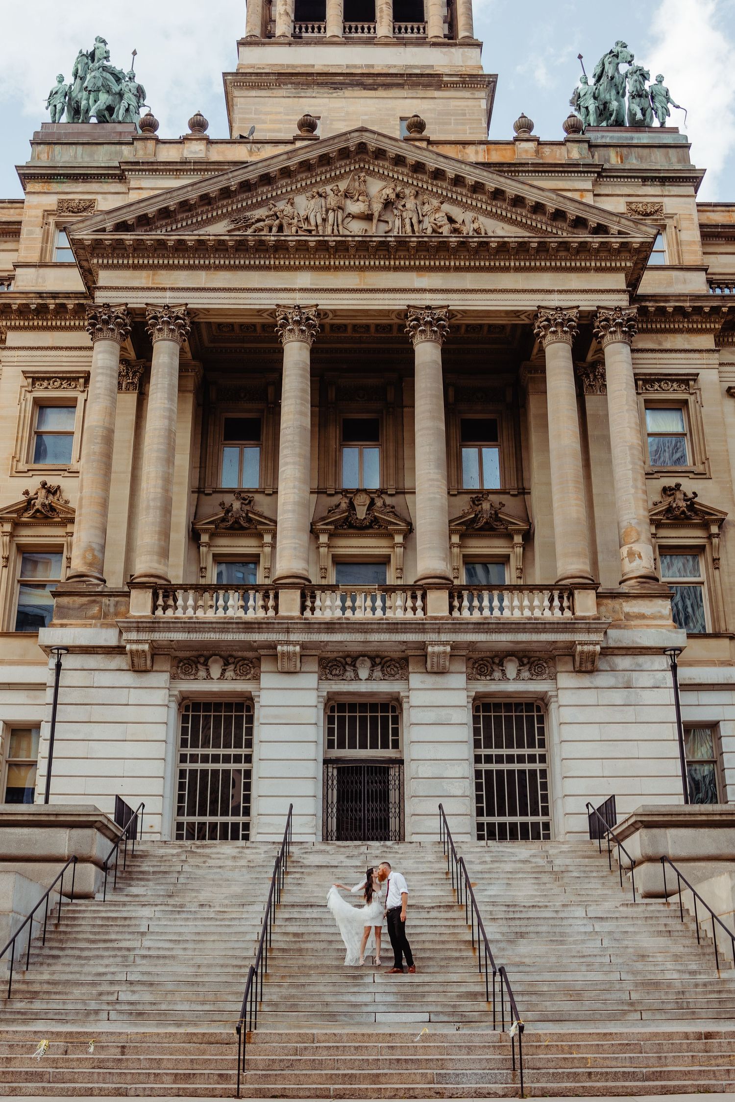 Wedding photo taken on grand steps of historic government building with classical architecture.