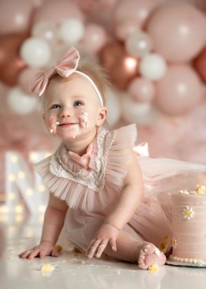 Sweet first birthday celebration with pink balloons and matching cake in delicate pastel tones from a minneapolis cake smash photographer