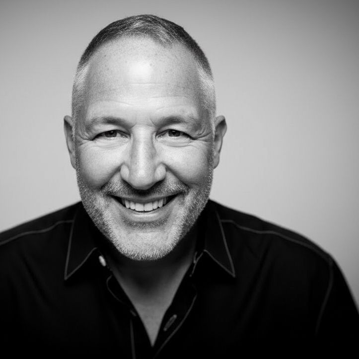 Black and white portrait photograph showing Darrek Robertson wearing glasses and a dark shirt against a light background