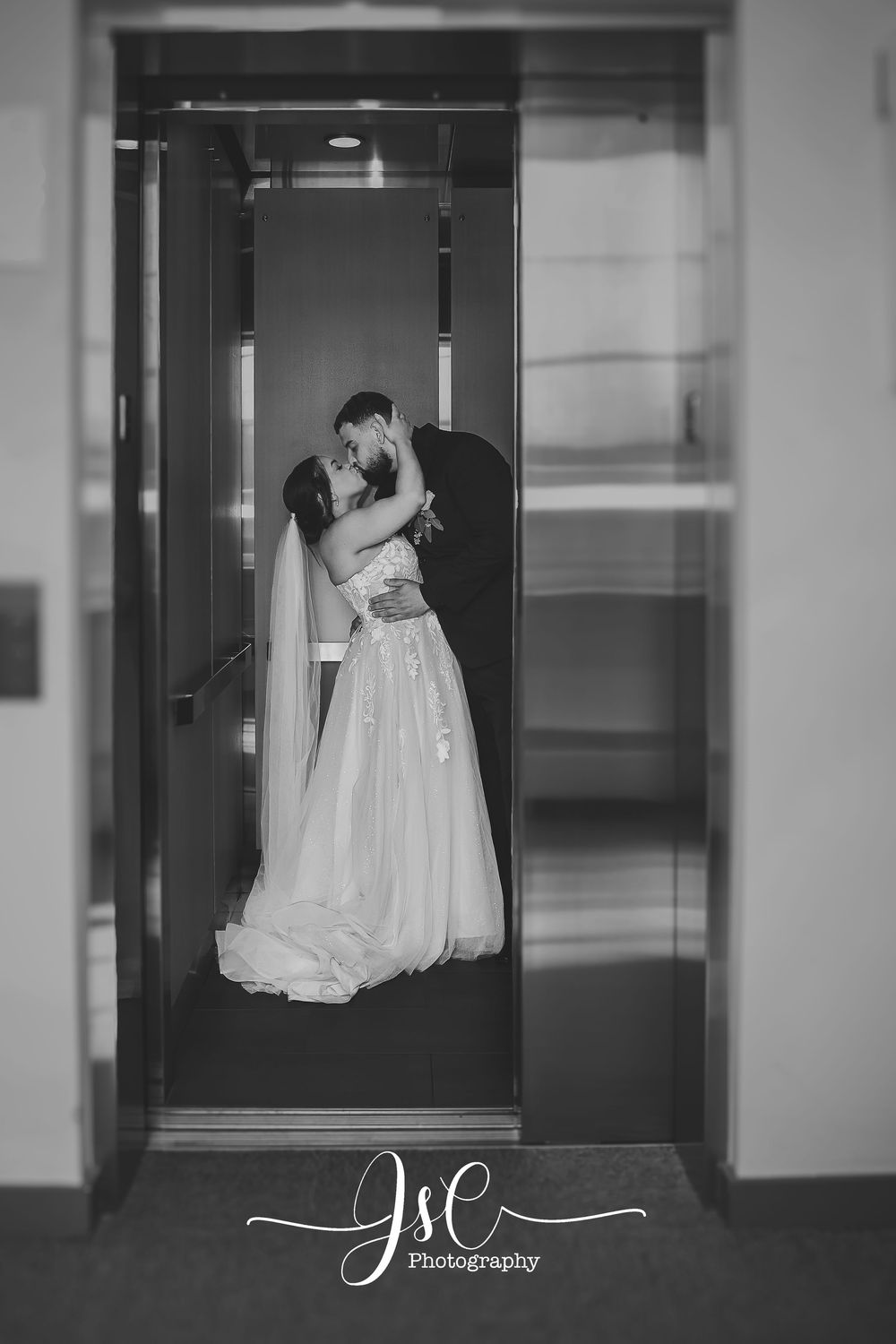 Black and white wedding photos captured in modern building hallway.