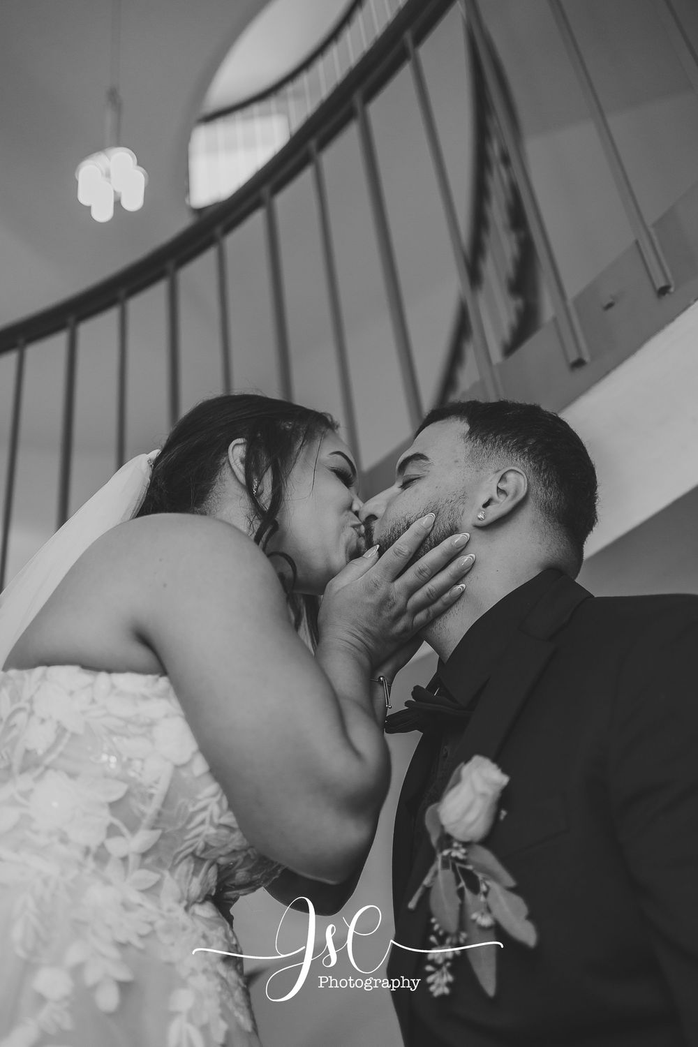 Dramatic black and white wedding kiss series on staircase.