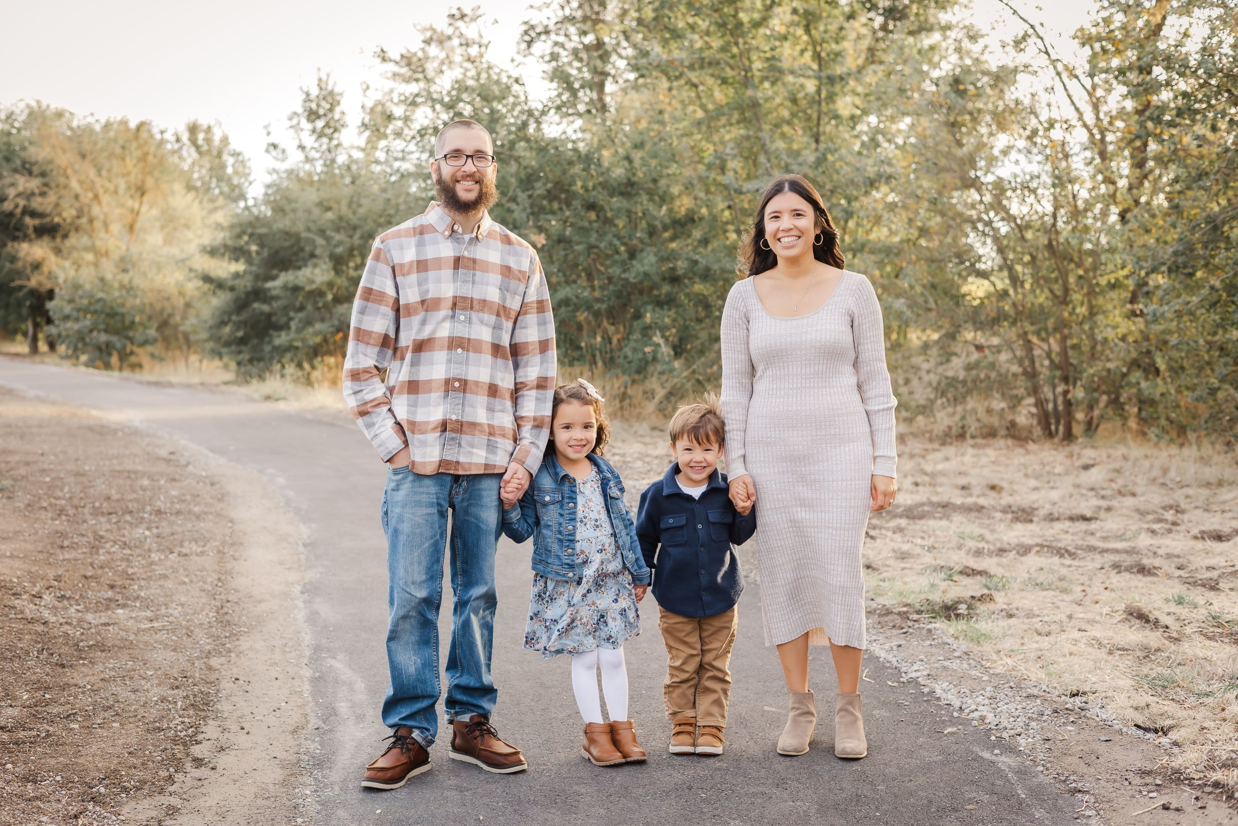 two parents and two kids walking holding hands on a long path in a fall setting at golden hour in sonoma county. fall mini session.