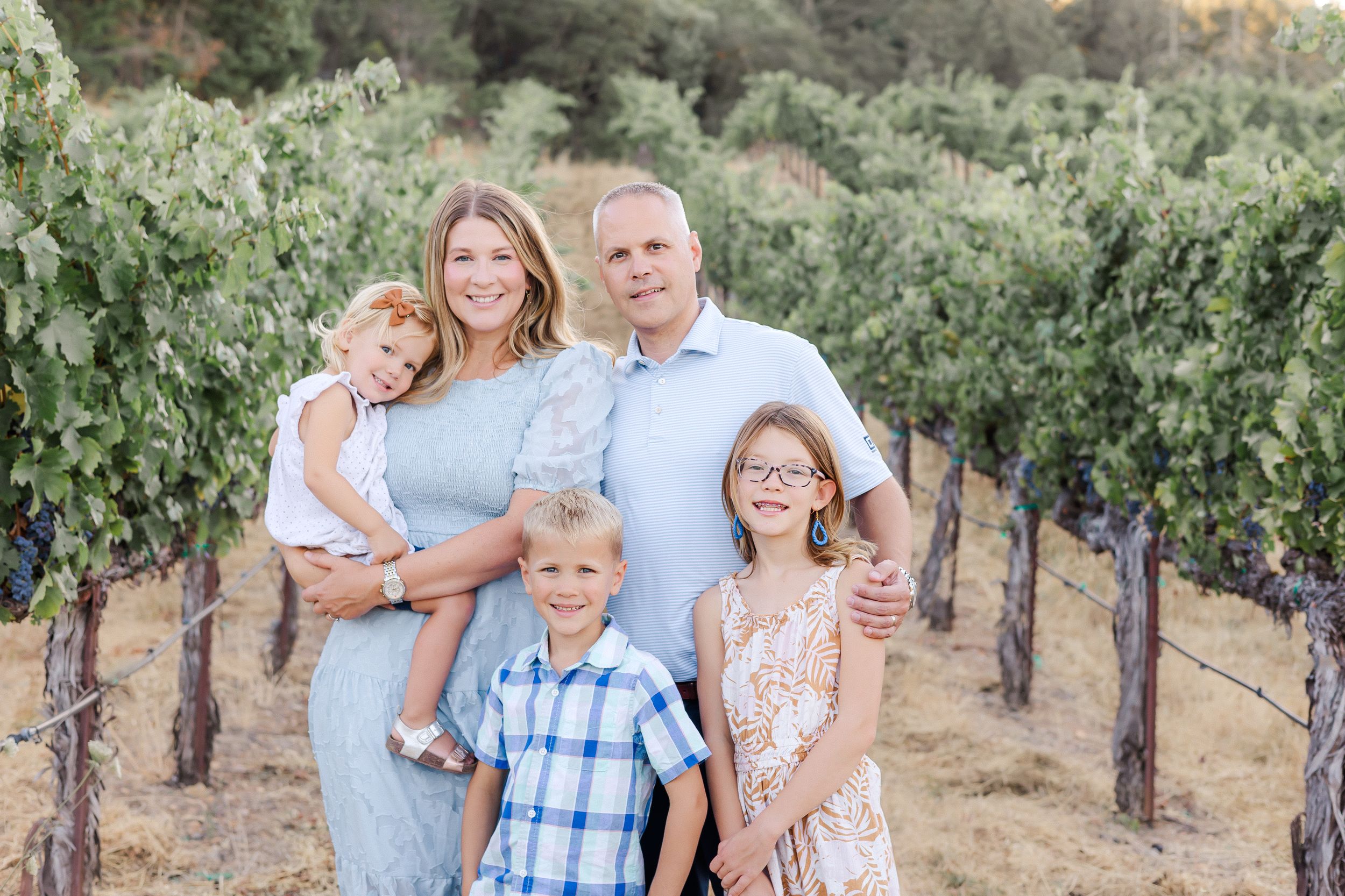 family of give smiling and cuddling in a vineyard at sunset in Sonoma County, California at golden hour. Geyserville mini session.