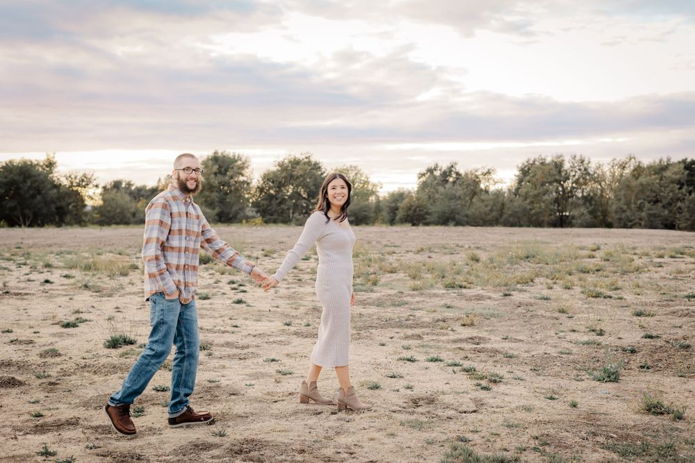 couple holding hands and walking in the sunset in Sonoma County. golden hour in an open field. fall photos