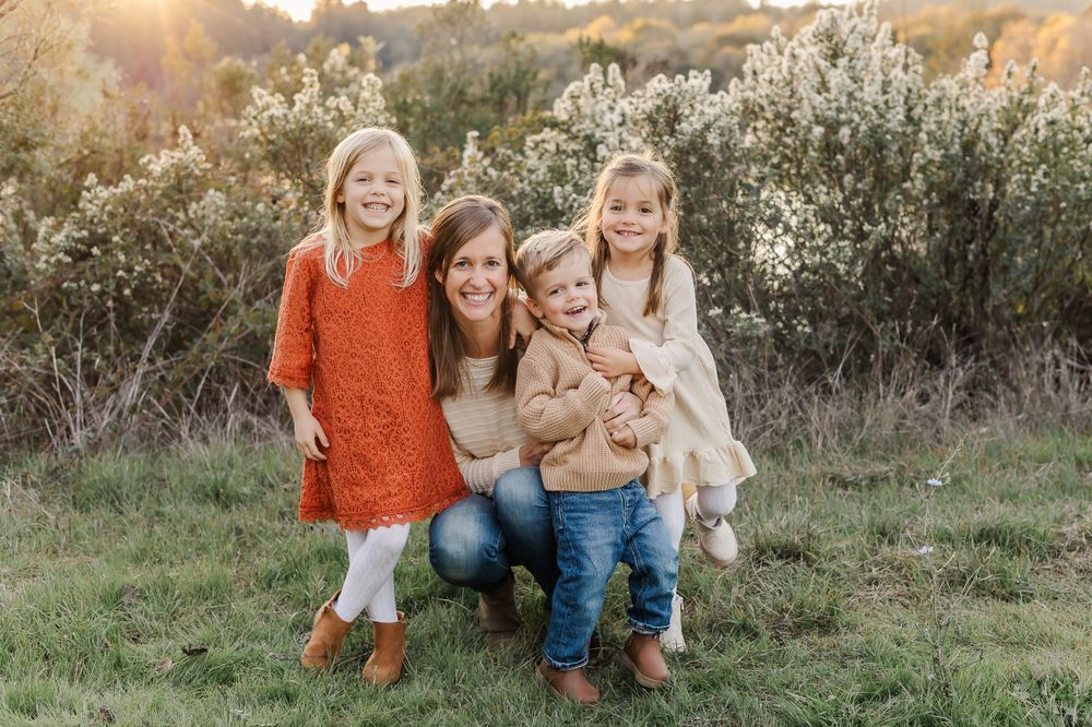 mom and 3 kids close together, smiling in front of flowers at golden hour in a fall mini session for holiday cards in Sonoma County