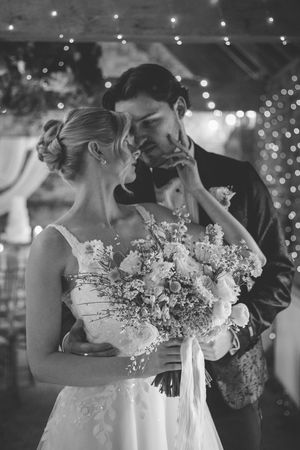 Black and white wedding photos show a romantic first dance moment between newlyweds under twinkling lights.