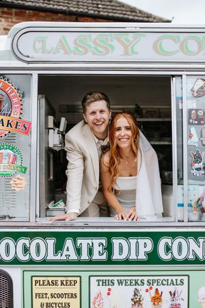 Smiling pair lean out of a vintage ice cream van window displaying 'Chocolate Dip Cones' and 'Classy Co' signage.