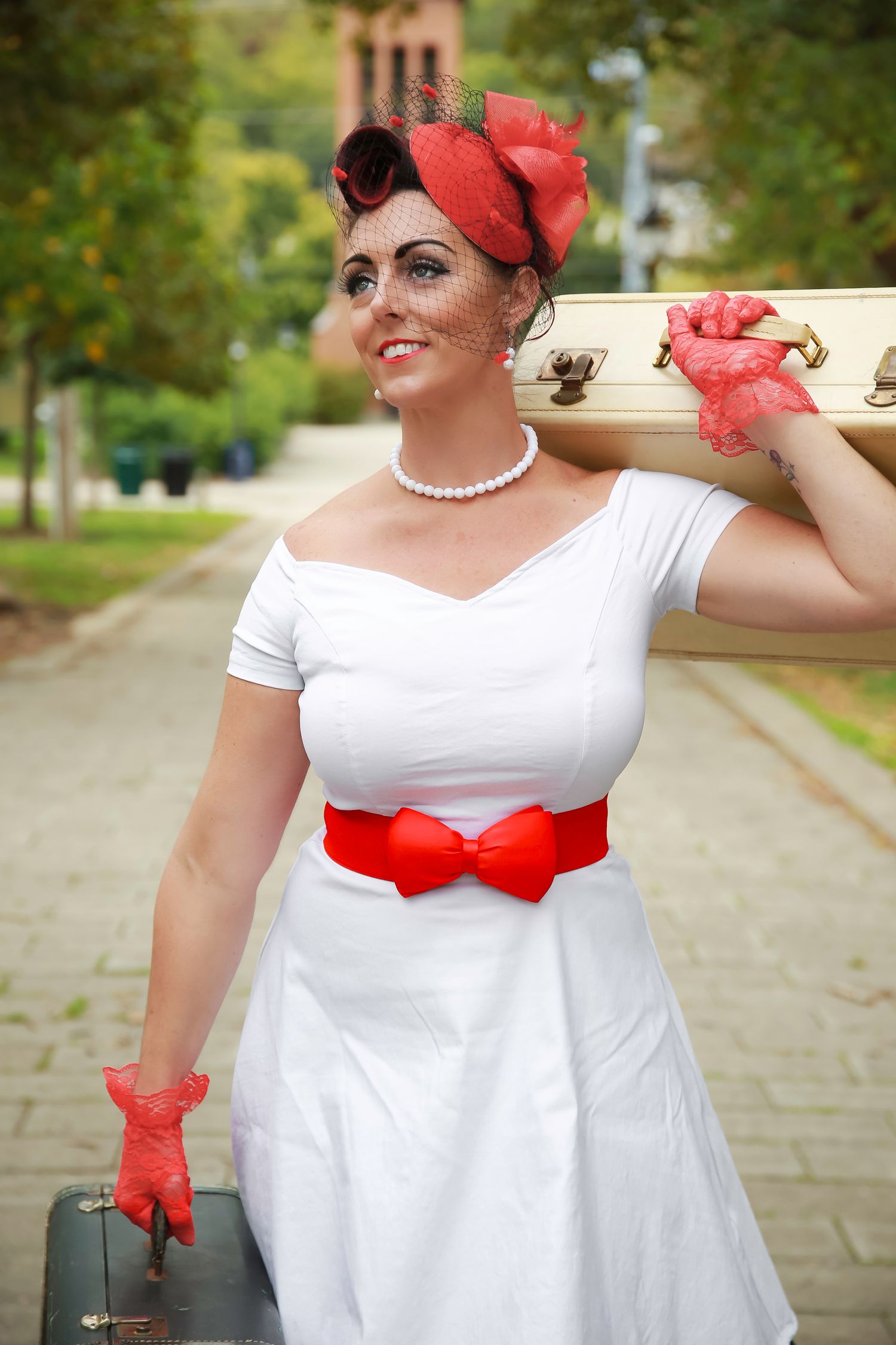 A retro-styled outfit featuring a white dress with red accessories including a bow belt, gloves, and headpiece.