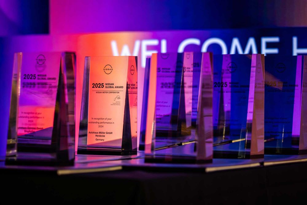 Crystal-clear photo of the 2025 Nissan Global Award trophies displayed under vibrant purple and orange event lighting.