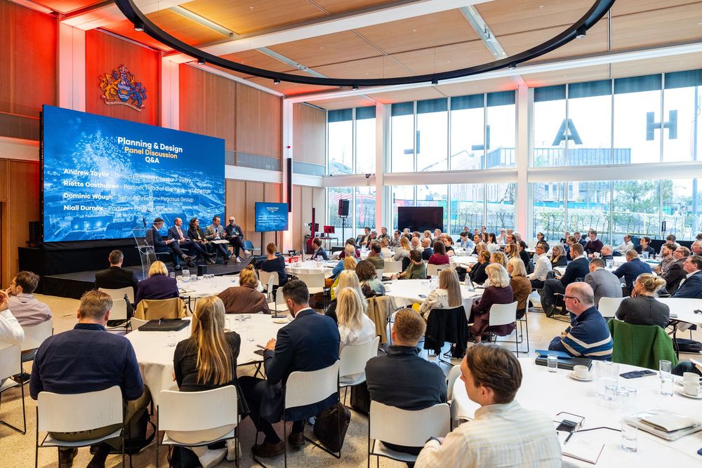 A large audience seated for a planning and design panel discussion in a bright, modern conference venue.