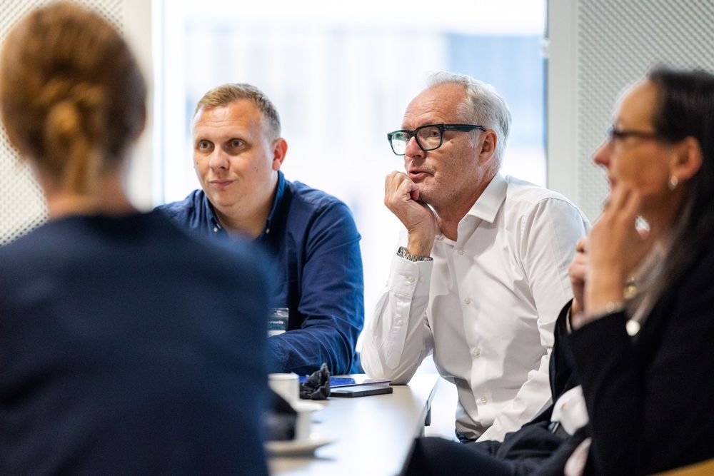 Business professionals engaged in a meeting, listening attentively during a discussion around a conference table.