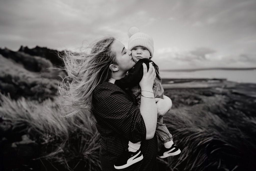 Family photographer Taranaki, Mum cuddling at babay at sunset on Taranaki beach