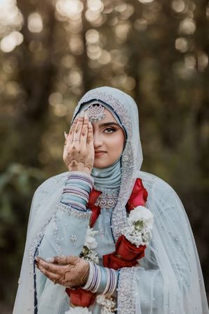 Close-up shots of a bride in an embroidered white hijab and red dress making elegant hand poses against a blurred background.