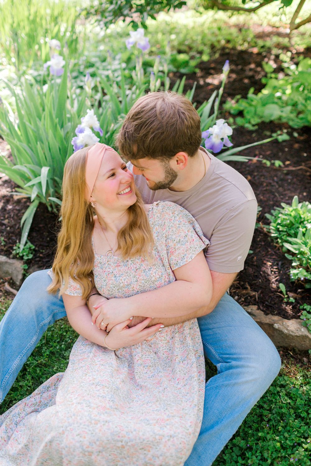 Couple sharing a tender moment in a lush garden blooming with purple iris flowers.