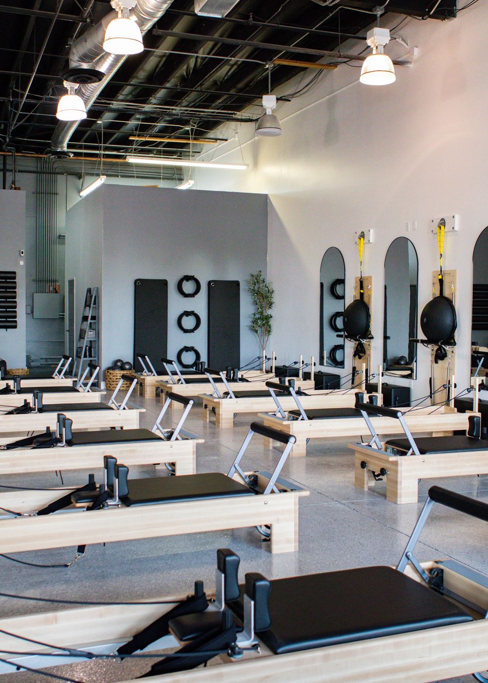 Clean modern pilates studio with reformer machines and minimalist gray and white design.