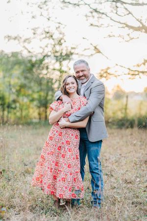 A romantic autumn portrait of a couple embracing in a sunlit field in Monroe Georgia.