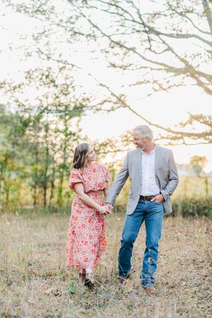 A couple shares a tender moment while walking through a golden sunset field in Monroe Georgia.