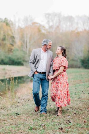 A couple takes a romantic stroll through an autumn field at sunset in Monroe Georgia.