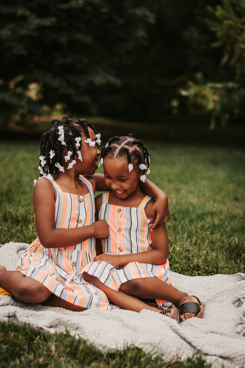 sisters sitting on a blanket outside in summer