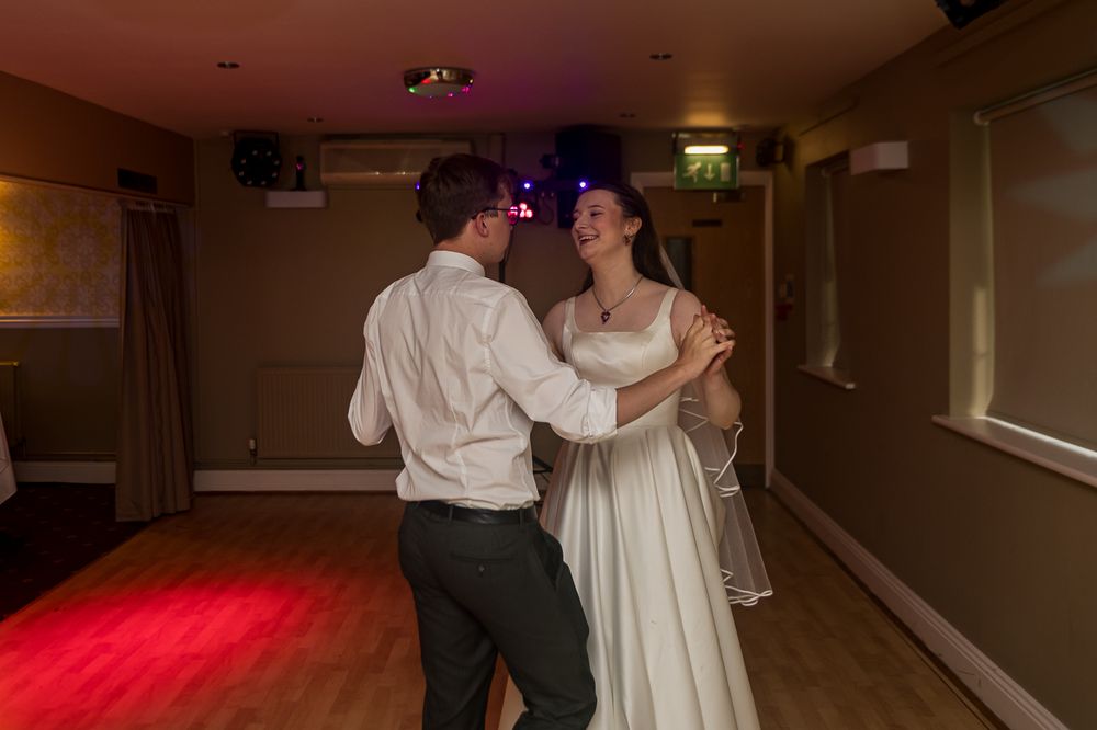 Bride and groom share their first dance in a warmly lit wedding reception venue.