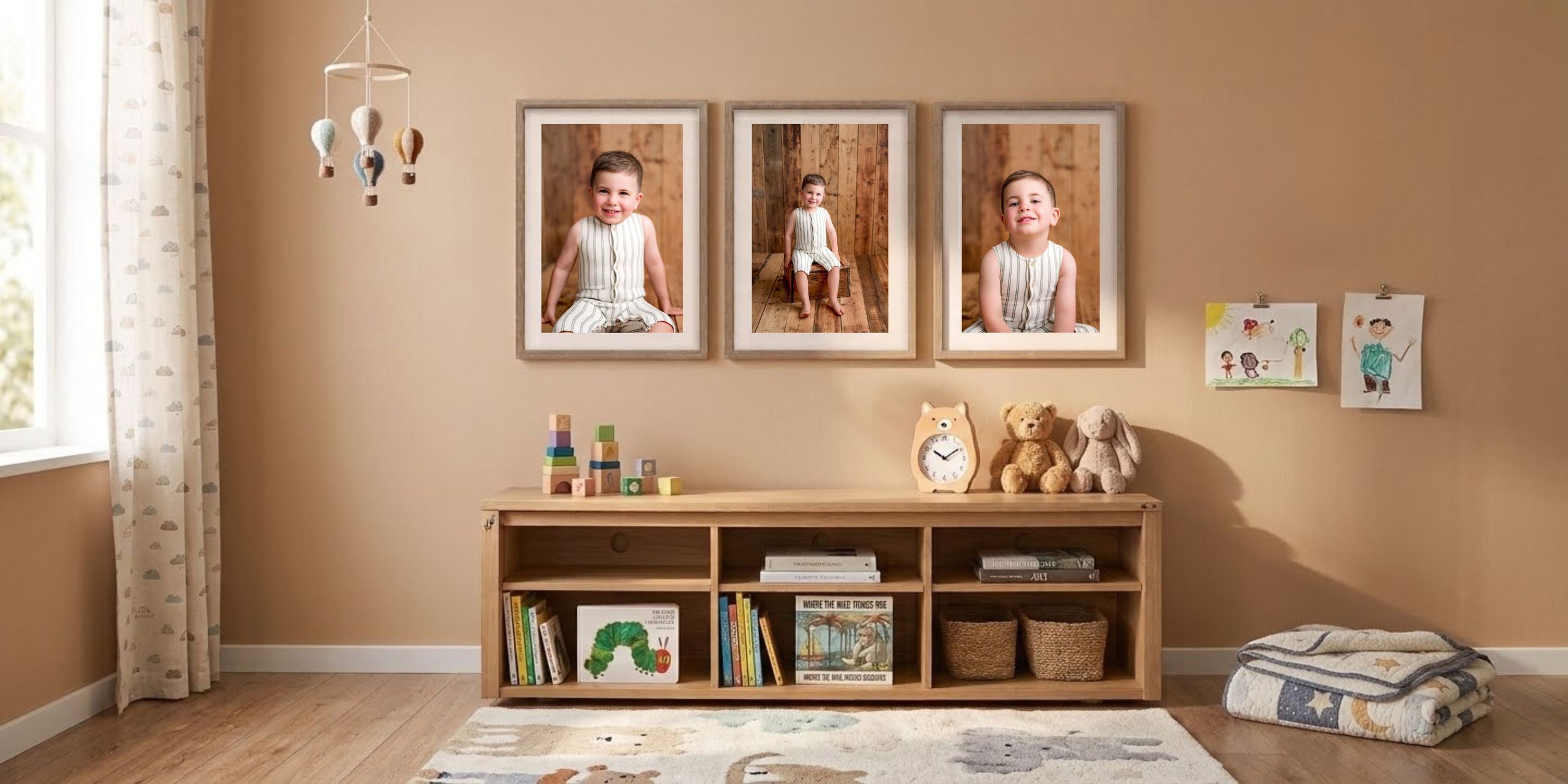 Cozy nursery with three framed child portraits above a wooden shelf holding books, baskets and toys, plus a plush rug and teddy bears.