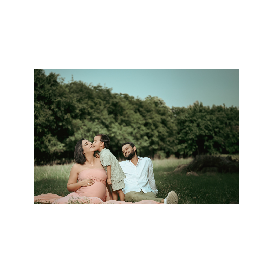 Sun-drenched outdoor maternity photo in natural meadow setting.