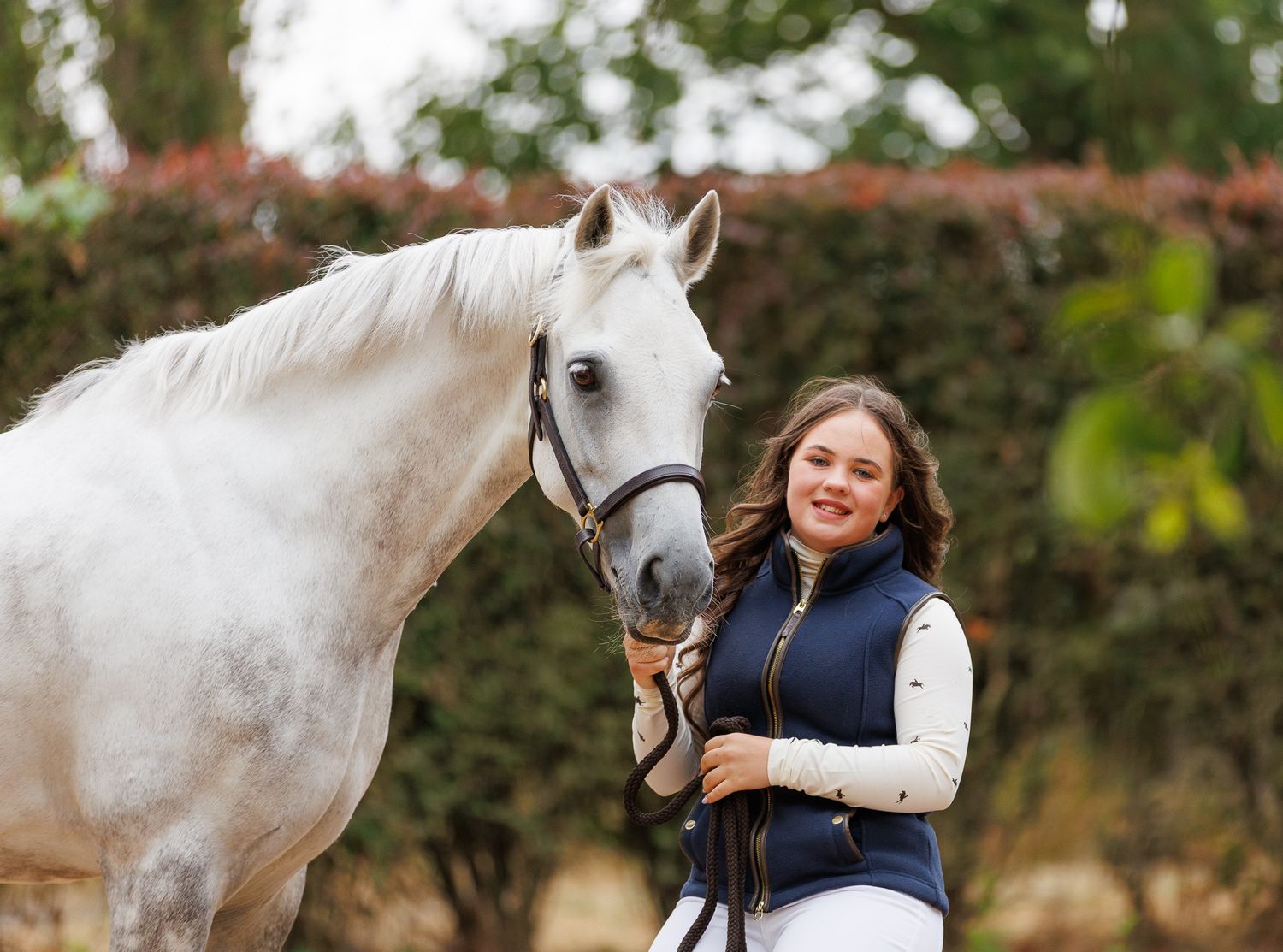 A horse and its rider enjoy an outdoor photoshoot session near rustic wooden fencing on a sunny day.