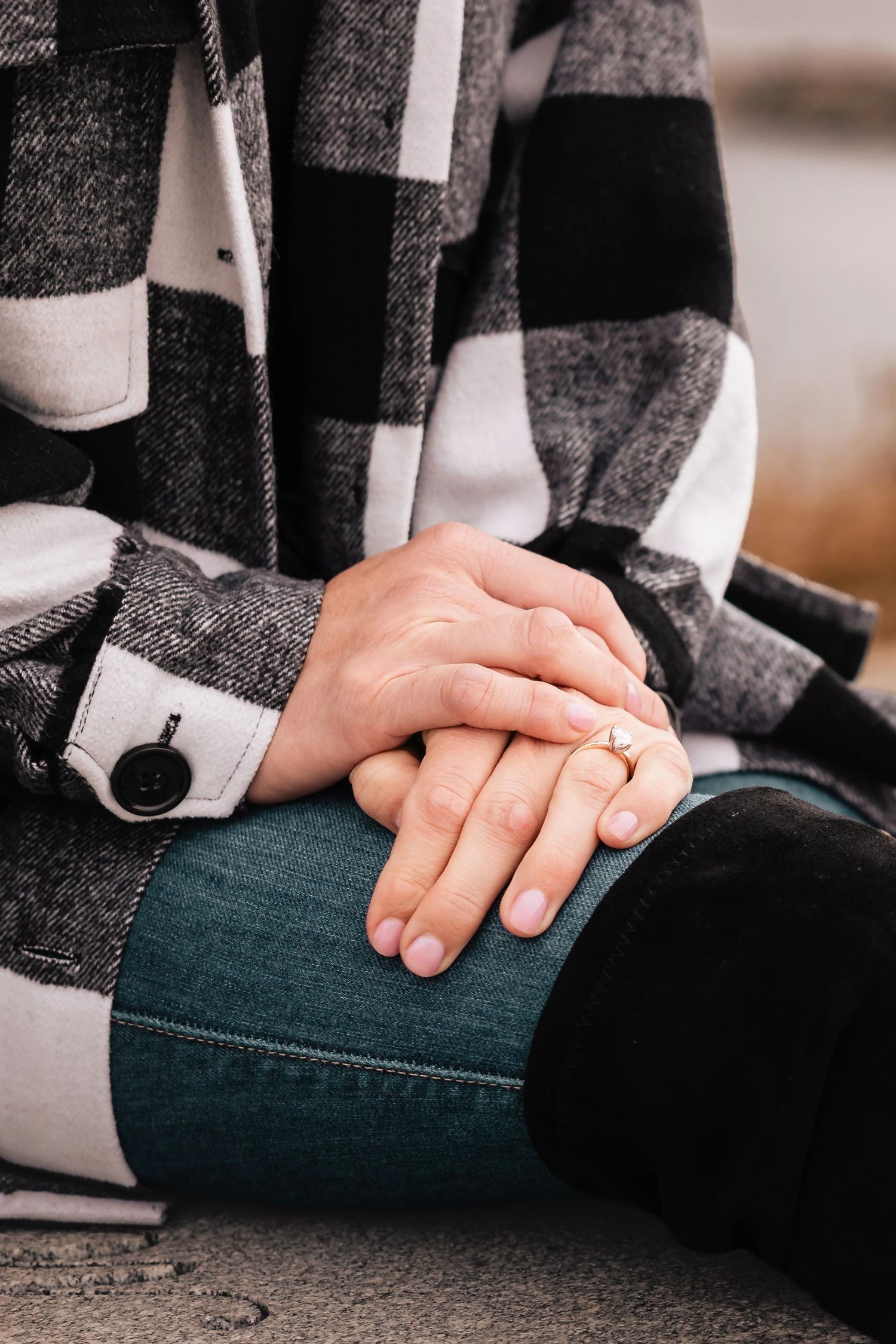 Two people's hands clasped together in an intimate gesture, one wearing a wedding ring. Engagement at Rockport Harbor, Rockport, MA