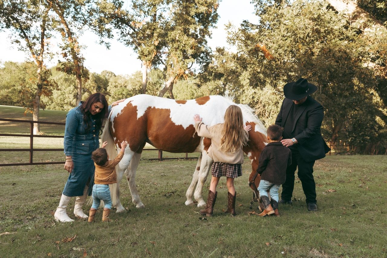 Family of five interacting together in their western outfits at Windmill Stables in Richardson, TX.