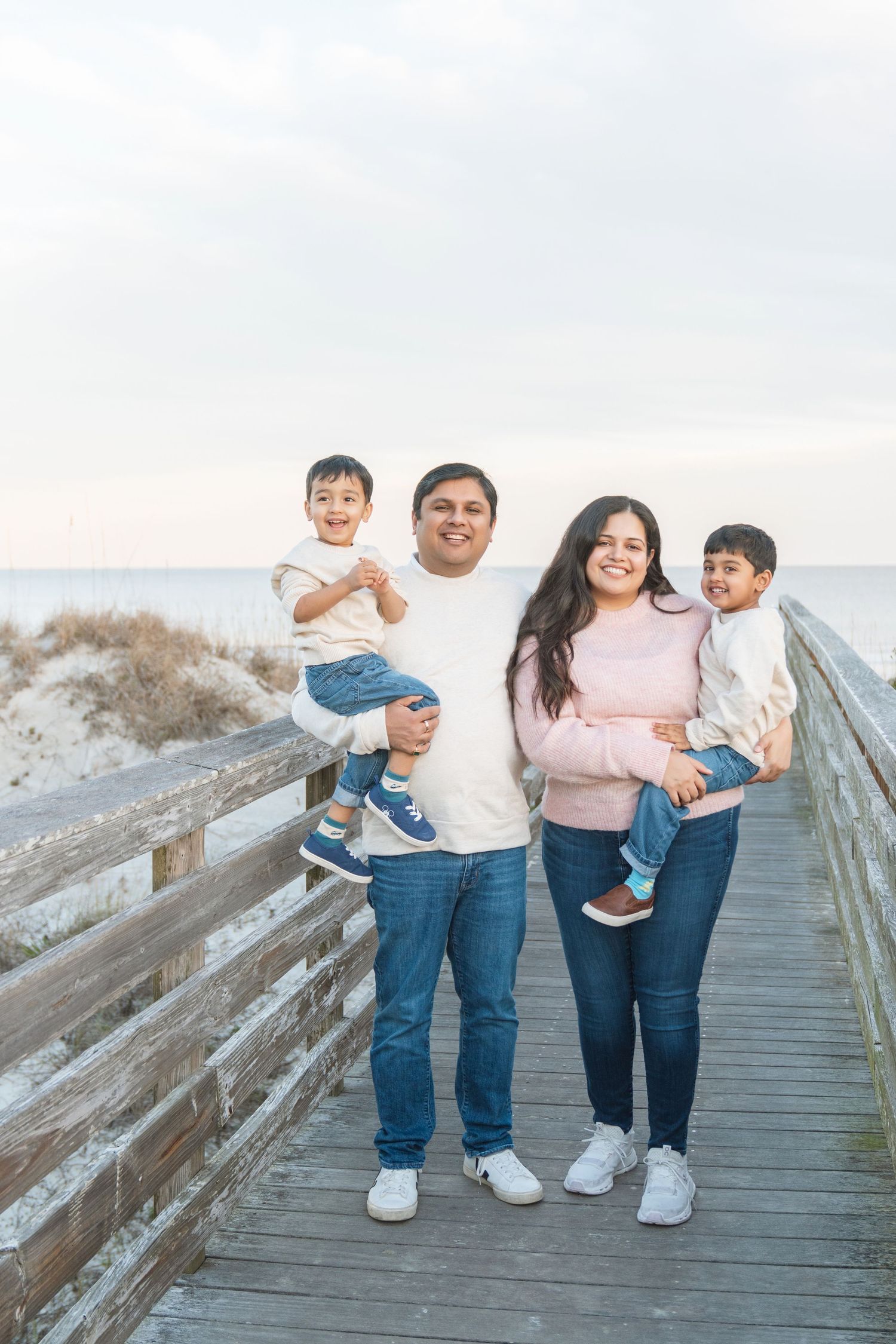 Parents and children embracing beside the ocean during a family portrait session with Lindy Rebro Photography.