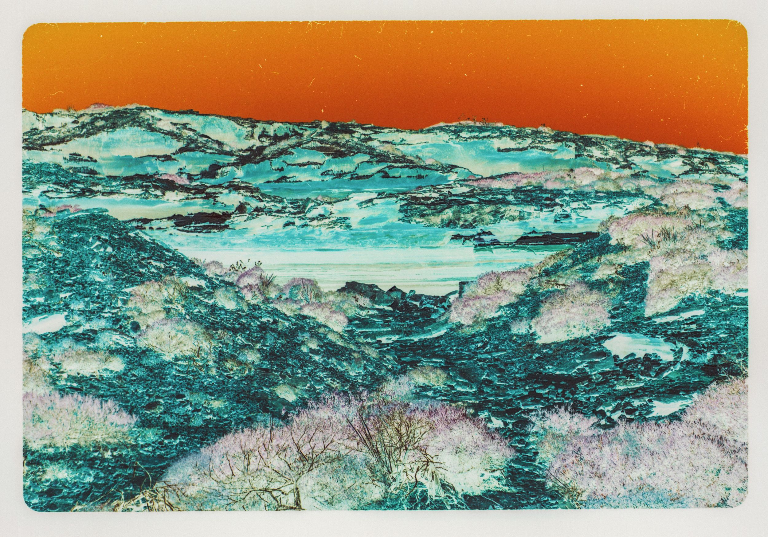 Colorful aerial landscape print featuring teal rocky terrain with pink trees and a vivid orange sky.