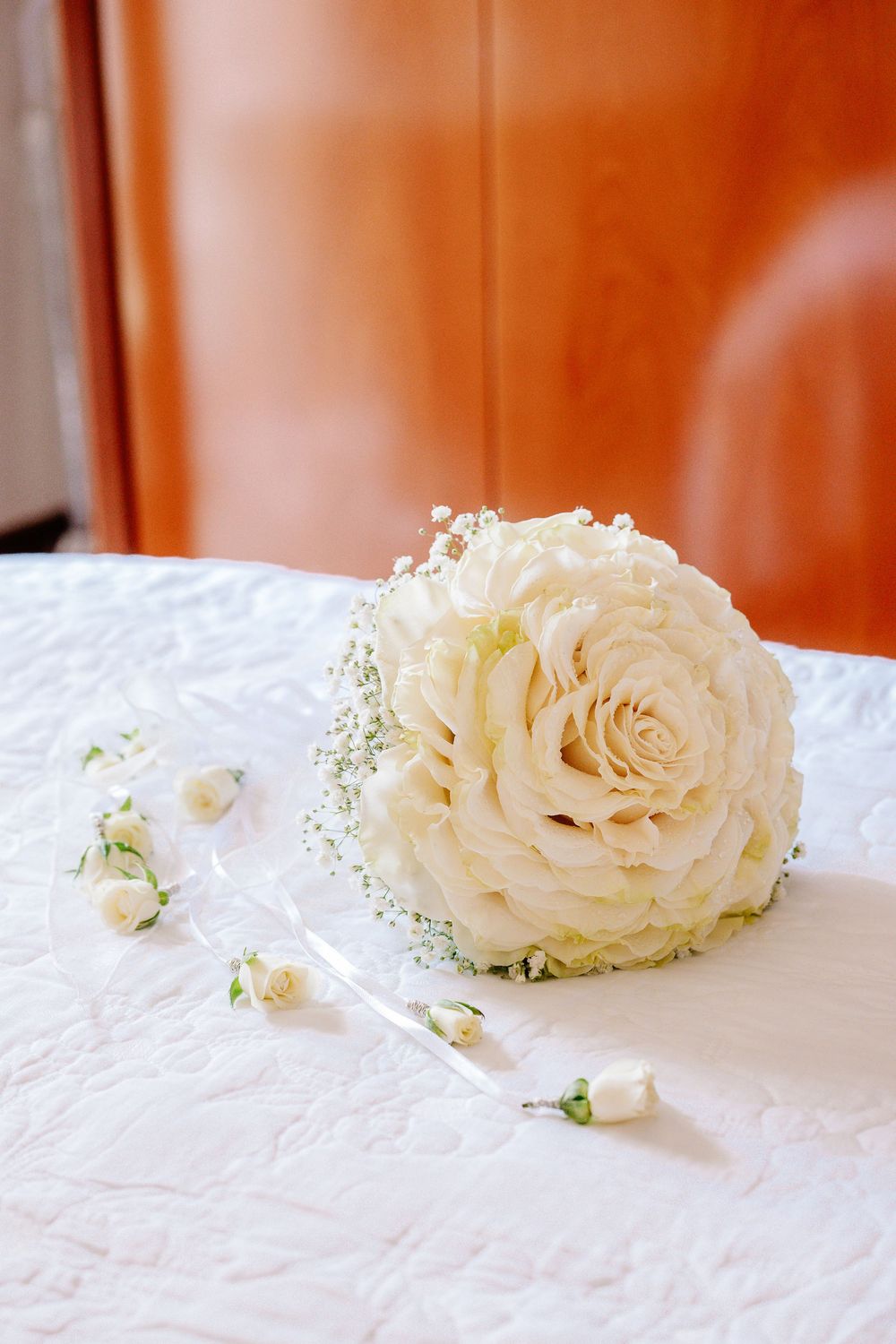 Elegant bridal bouquet of white roses and baby's breath on a white tablecloth.