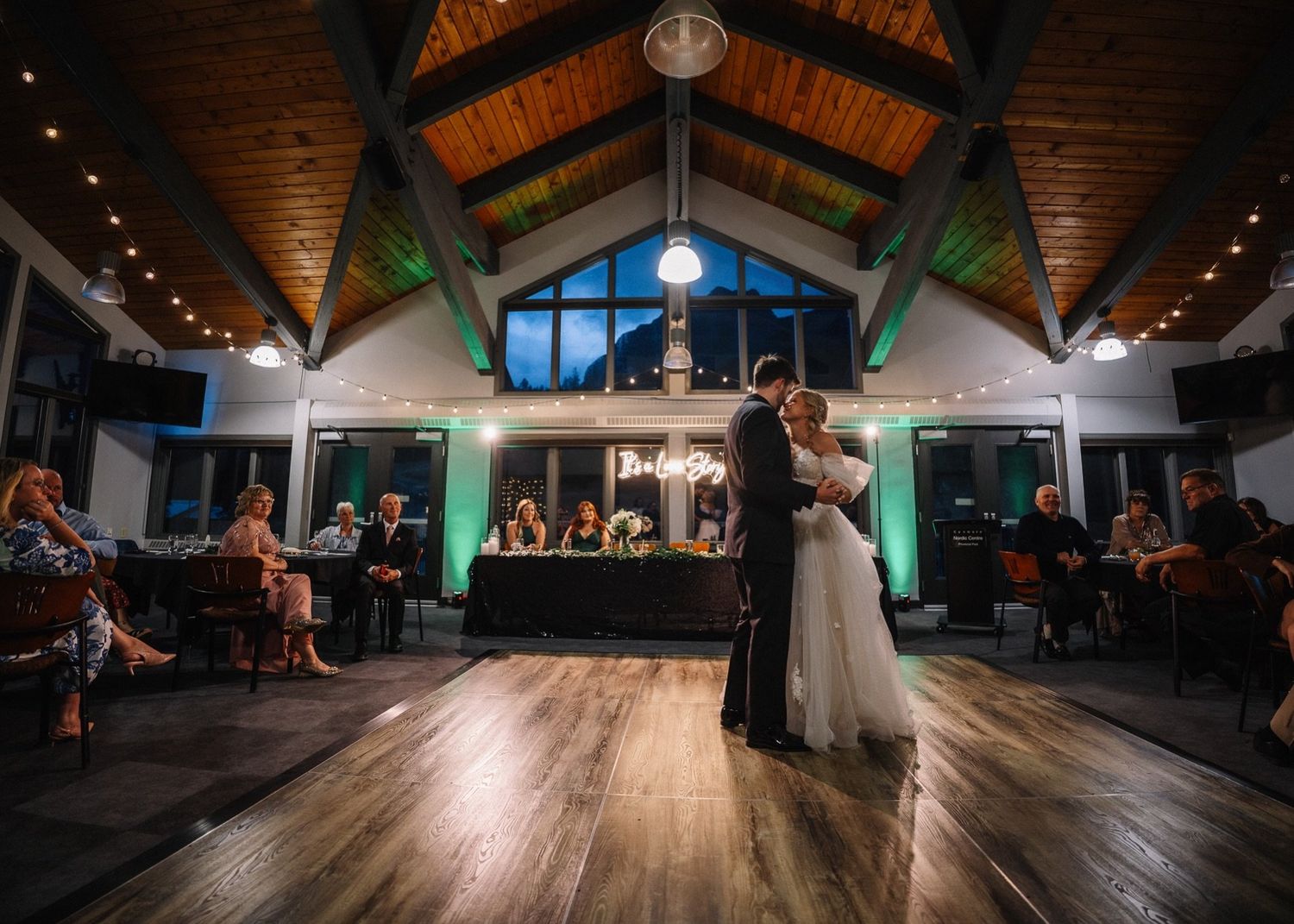 First dance in the Rundleview Room at the Canmore Nordic Centre under vaulted wood ceilings and string lights