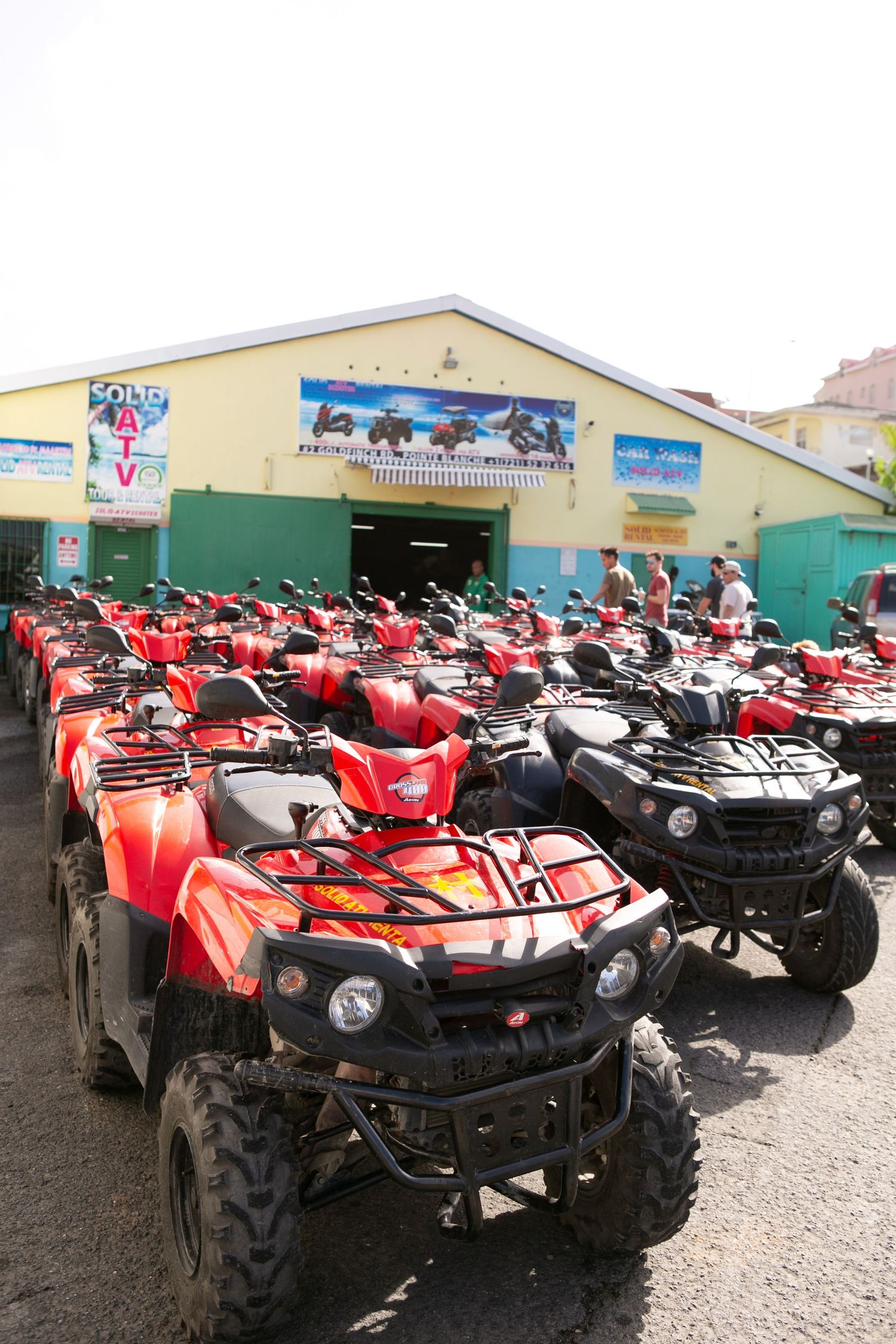 Rows of red ATVs parked outside a colorful rental shop, ready for off-road tours in a sunny destination.