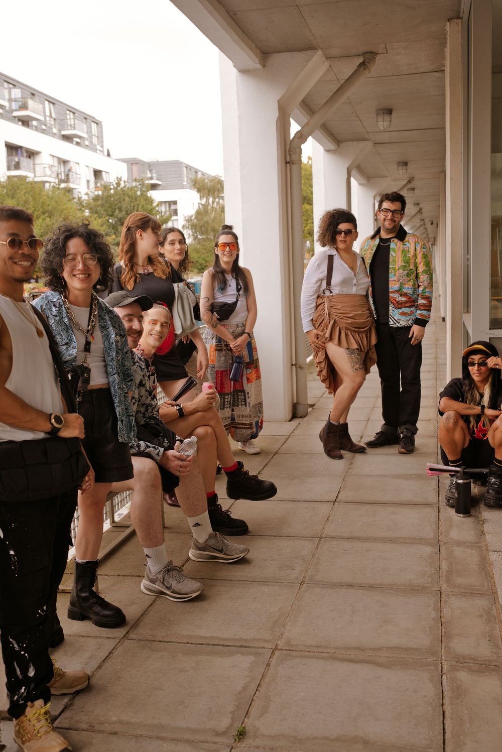 A diverse group of stylishly dressed young people gathered on a covered outdoor walkway in an urban setting.