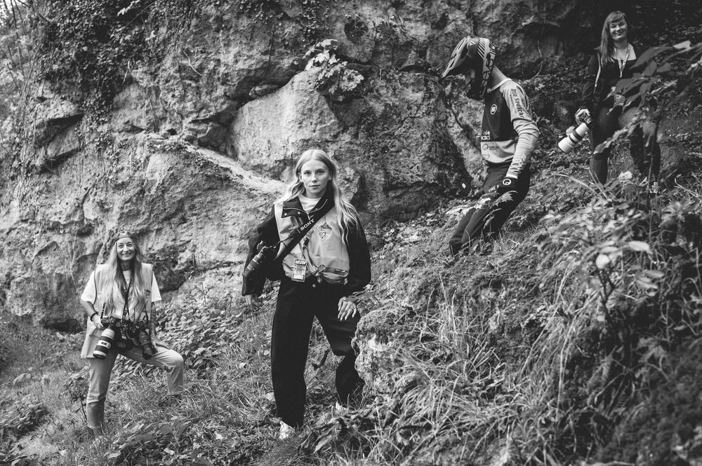 Black and white photo of a rock band posing on a rocky hillside, with long-haired musicians in casual 1970s attire.