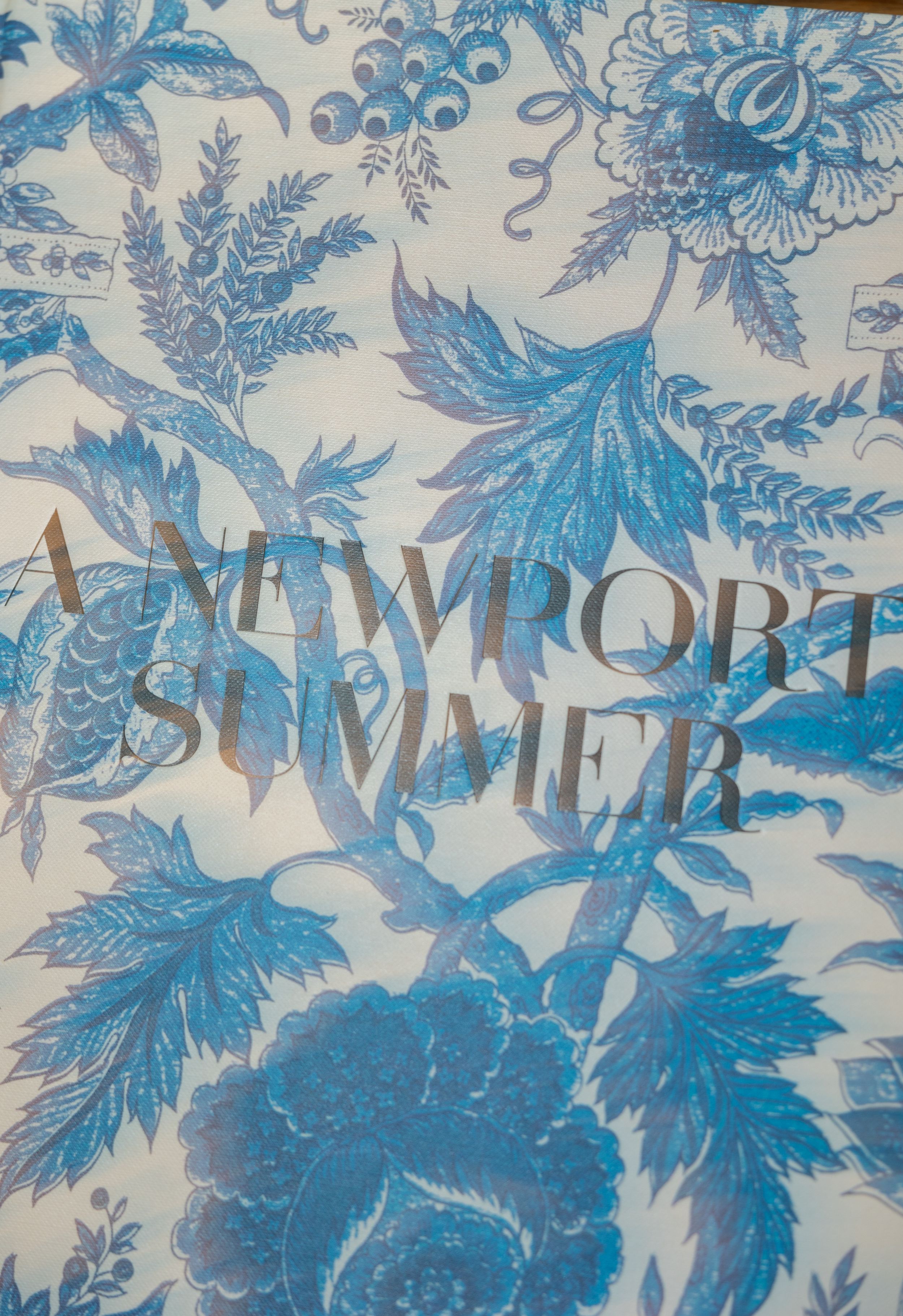 Blue and white floral toile pattern with elegant Newport Summer text overlay.
