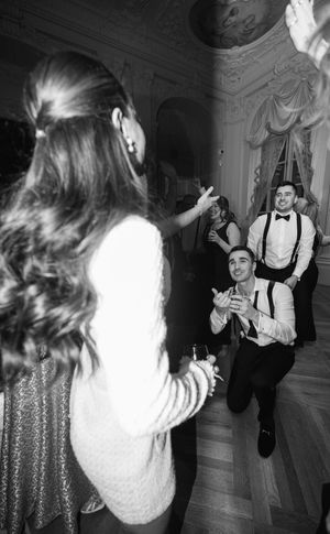 Guests dancing and celebrating at elegant black and white wedding reception in ornate ballroom.