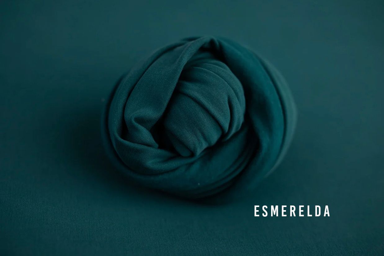 Esmerelda teal green fabric wrap coiled into a rose shape on a matching dark teal background.