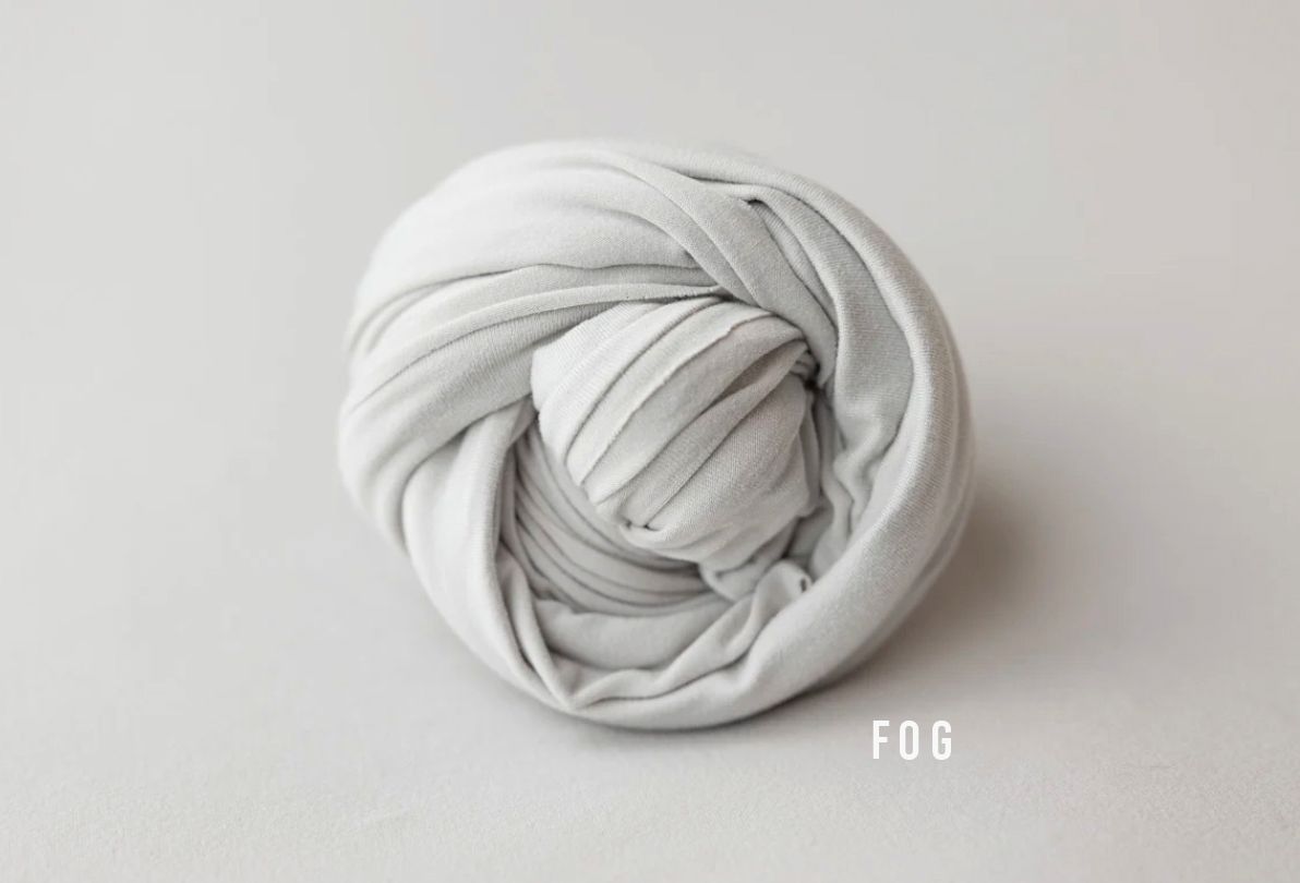 A soft gray fabric wrap coiled neatly, labeled FOG, ideal for newborn photography props.