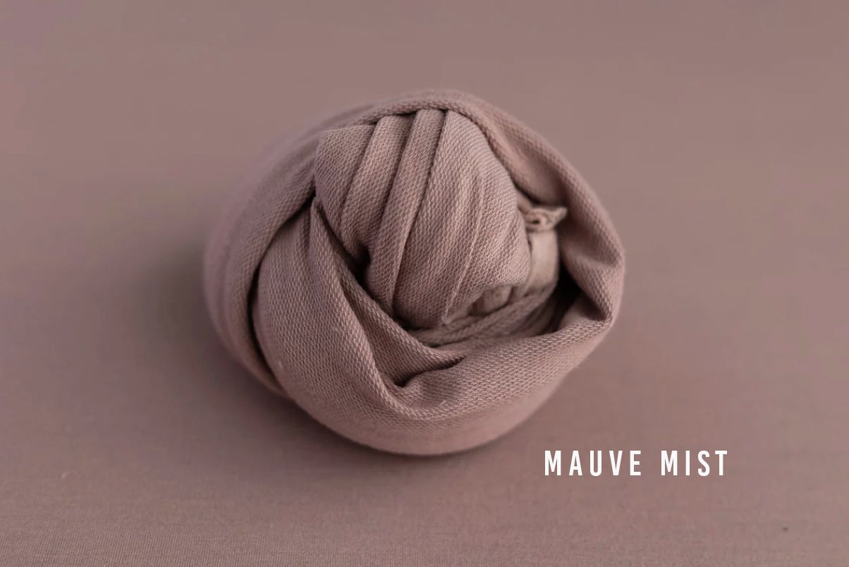 Mauve mist soft fabric wrap coiled into a round bundle on a mauve background for newborn photography.