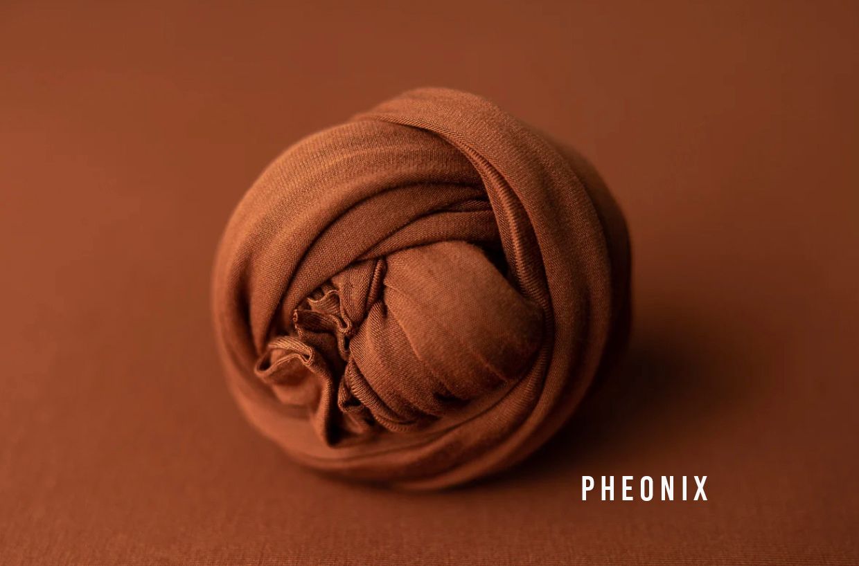 Pheonix warm rust brown fabric wrap rolled into a ball on a matching brown background for newborn photography.